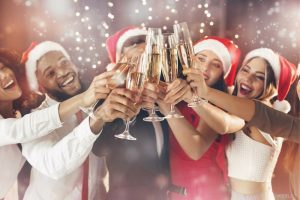 Group of friends toasting champagne at a holiday party, wearing Santa hats.