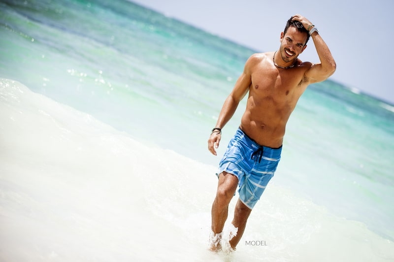 Shirtless man walking on the beach
