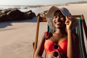 Happy young woman sitting in a sling chair at the beach.